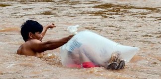 Crianças de uma vila no Vietnã atravessam rio de águas bravas em sacos plásticos para chegar à escola