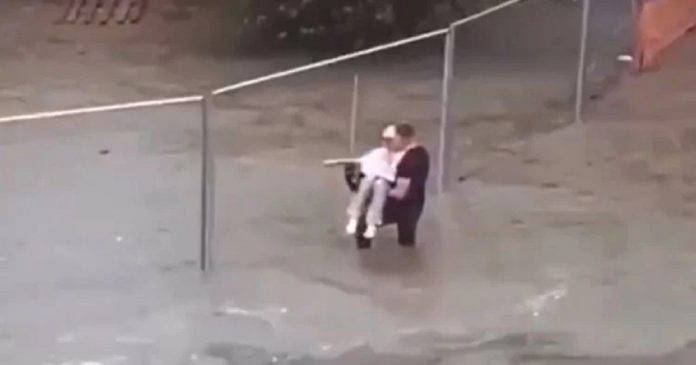Homem resgata idosa agarrada a cerca enquanto as enchentes sobem ao redor dela