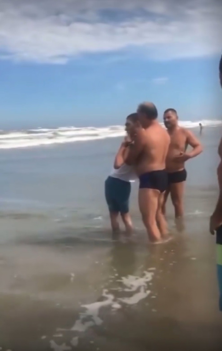 psicologiasdobrasil.com.br - Homens ajudam pai a levar seu filho com deficiência para tomar seu primeiro banho de mar